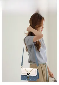 Detail view of heart-quilted crossbody bag with light blue and white contrast panels
