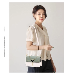 Detail view of heart-quilted crossbody bag featuring a golden chain and character charm