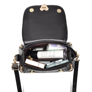 Black leather crossbody bag with gold heart clasp showing large storage capacity