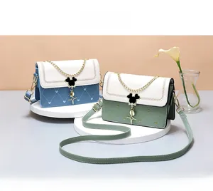 Detail of crossbody bag with Mickey-shaped clasp and heart-quilted texture on round stand