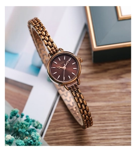 Détail macro de la montre à quartz GEDI en bronze avec bracelet à maillons sur une table en bois