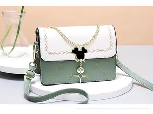 Detail of green crossbody bag showing heart-shaped stitching and mouse silhouette buckle