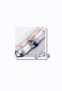 Détail de la lunette en or rose sertie de cristaux et couronne en saphir bleu sur fond blanc