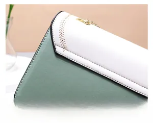 Detail of cream and sage green leather stitching on a compact square crossbody bag