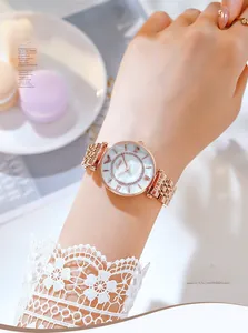 Close-up of rose gold quartz watch with white mother-of-pearl dial on a woman's wrist