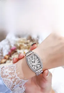 Primo piano dell'orologio tonneau argento di lusso con lunetta in strass sul polso femminile