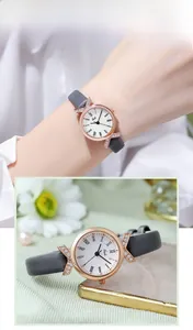 Close-up of rose gold watch with X-shaped diamond accents and grey leather strap