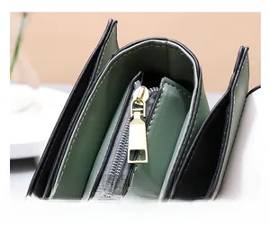 Detail of smooth golden metal zipper and dark green PU leather on a small square bag