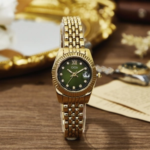 Elegante orologio al quarzo in oro con quadrante verde e datario su scrivania in legno
