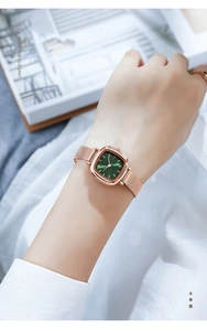 Close-up of elegant rose gold mesh band watch with a green square sunburst dial