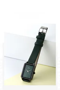 Dettaglio dell'orologio rettangolare verde scuro con lancette oro rosa e cinturino in pelle