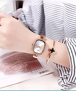 Detail of rose gold vintage watch and four-leaf clover bracelet on woman wrist