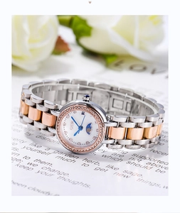 Détail d'une montre bicolore avec lunette en strass et aiguilles bleues sur roses blanches