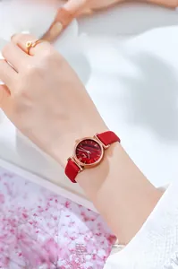 Close-up of elegant women's quartz watch with red strap and rose gold case on a wrist