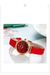 Detail of elegant red wood grain dial and thin leather strap on a golden quartz watch