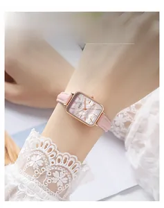 Macro shot of a pink leather watch strap with a golden square case on a lace sleeve