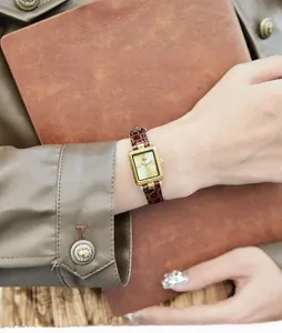 Dettaglio di un orologio rettangolare in oro vintage con cinturino in pelle marrone