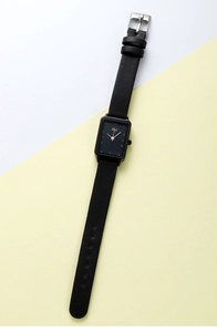 Dettaglio di un orologio quadrato vintage con cinturino in pelle nera e lancette d'oro
