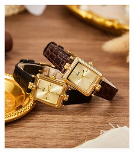 Dettaglio di orologi quadrati vintage dorati con cinturini in pelle nera e marrone