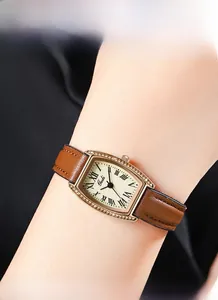Close-up of tonneau quartz watch with roman numerals and diamond-set gold bezel on wrist