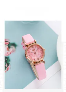 Detail of pink marble dial watch with rose gold case and leather strap on a floral base