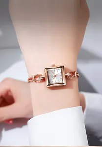Detailopname van roségouden vierkant horloge met gedraaide schakelarmband om de pols
