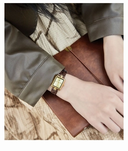 Primo piano dell'orologio vintage dorato con cinturino in pelle marrone al polso della donna
