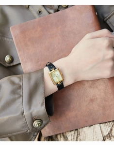 Dettaglio di un orologio vintage quadrato in oro da donna con cinturino in pelle nera al polso