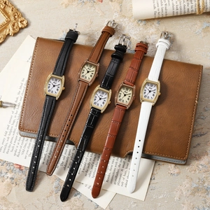 Close-up of Gedi quartz watches with roman numerals on leather notebook surface