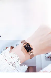 Detail of rose gold mesh strap and vintage square watch face with starry black dial