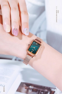 Macro shot of woman wearing a retro rectangular rose gold watch with green malachite dial