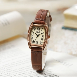 Vintage tonneau quartz watch with rose gold case and brown leather strap on book