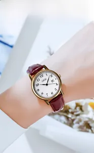 Close-up of minimalist retro women's watch with brown leather strap and gold-tone case