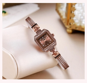Close-up of a vintage rose gold rectangular watch with a brown gradient dial and mesh strap