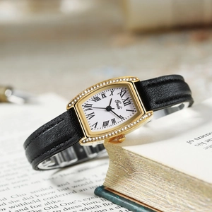 Close-up of vintage tonneau watch case with rhinestones and Roman numeral dial on leather