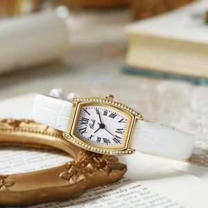 Detail of Gedi gold tonneau watch case with sparkling diamonds and white roman dial