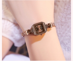 Detail view of a rose gold square watch with multi-strand metal chain strap on wrist