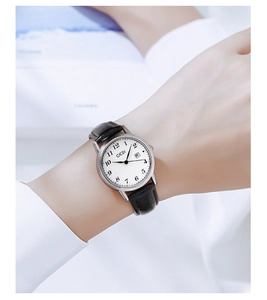 Close-up of retro silver quartz watch with white dial, date display and black leather strap
