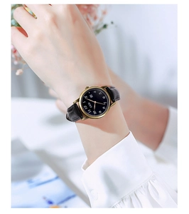 Detail of minimalist vintage lady watch with black leather strap and golden steel case