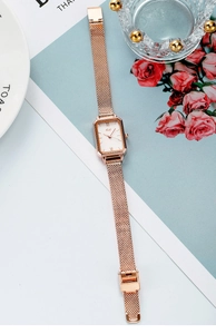 Detail of retro rectangular watch dial with rose gold mesh strap and Roman numerals