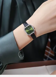 Detailed view of an octagonal green watch dial with a black leather strap on a wrist