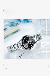 Montre femme élégante avec cadran noir et bracelet en acier argenté sur décor bleu