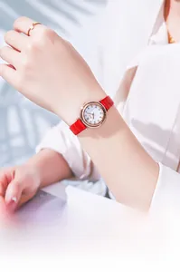 Detail of elegant women's watch with red leather strap and rose gold rhinestone dial