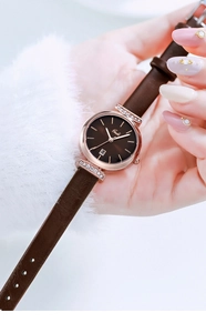 Detail einer roségoldenen Damenuhr mit braunem Lederarmband und Diamantbesatz