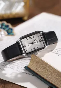Detail shot of vintage square quartz watch with black leather strap on a book