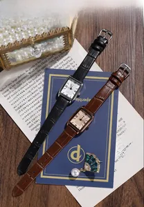 Close-up of retro rectangular quartz watches with black and brown leather straps on wood