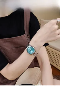 Detail shot of a minimalist silver stainless steel watch with a Tiffany blue dial on wrist