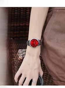 Close-up of elegant women's watch with red sunray dial and silver stainless steel strap