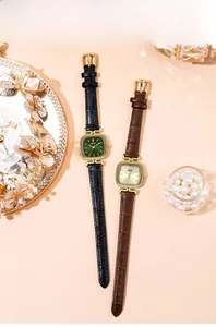 Detailed close-up of square quartz watches with crocodile pattern leather straps on elegant tray