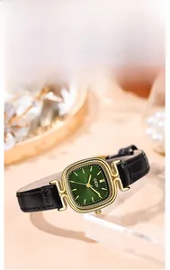 Detail of square gold watch case with emerald green sunray dial and black leather strap